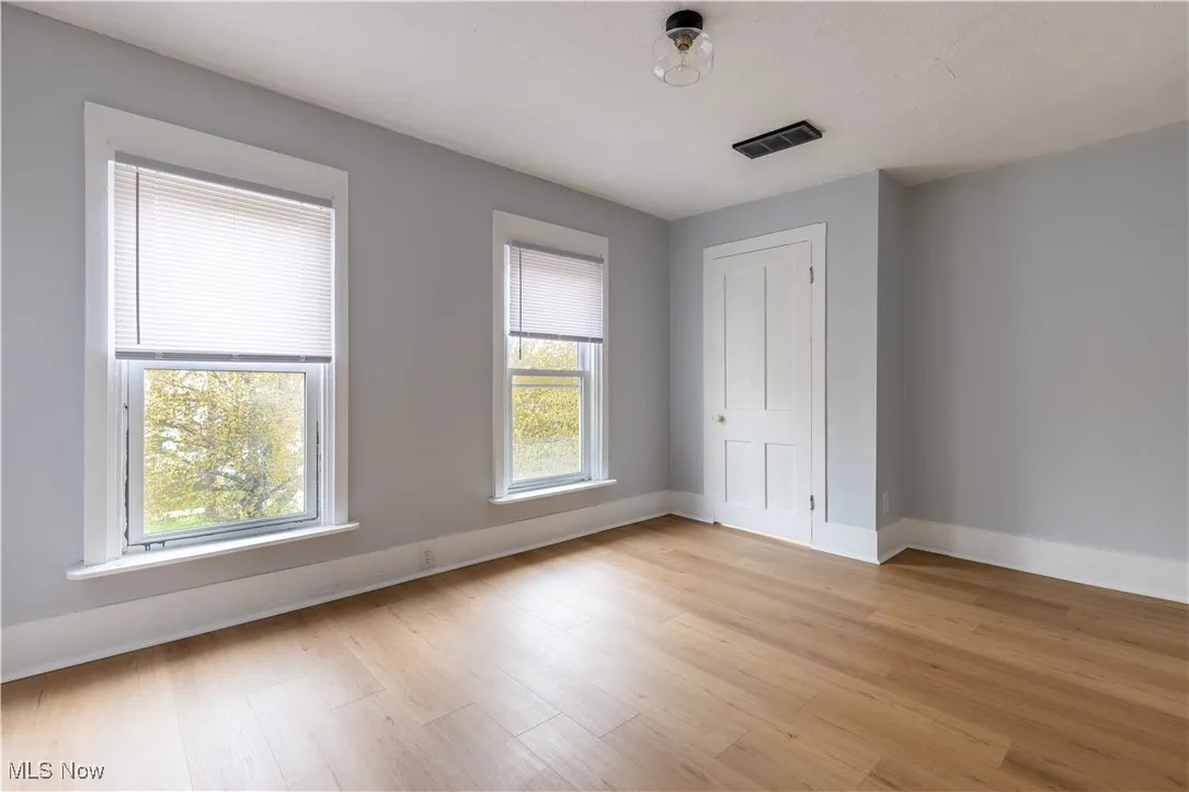 Unfurnished bedroom featuring multiple windows, light wood-type flooring, and baseboards