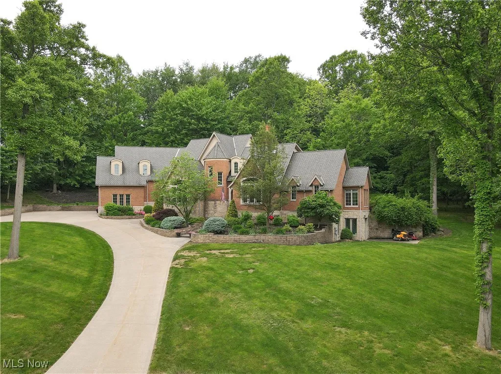 Country French  style home featuring brick siding, curved driveway, and a front yard