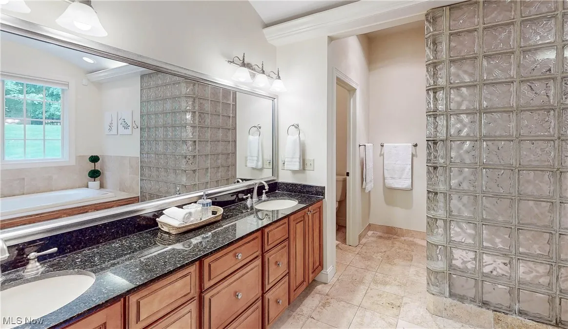 Full bathroom with double vanity, toilet, a garden tub, and tile patterned floors