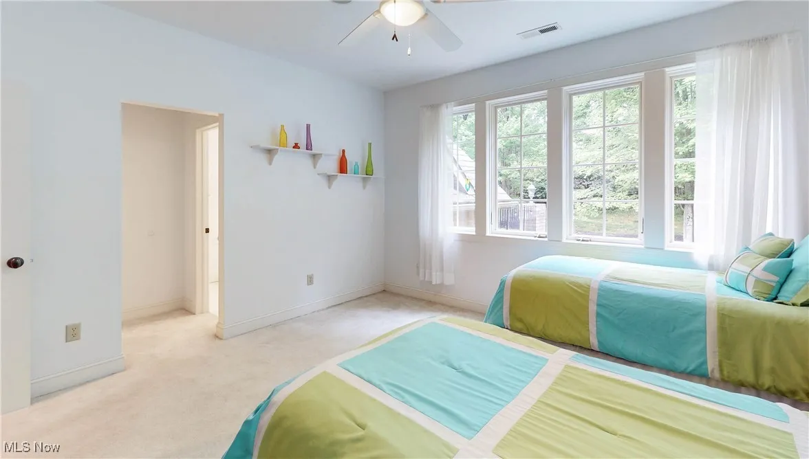 Bedroom featuring light colored carpet, baseboards, and ceiling fan