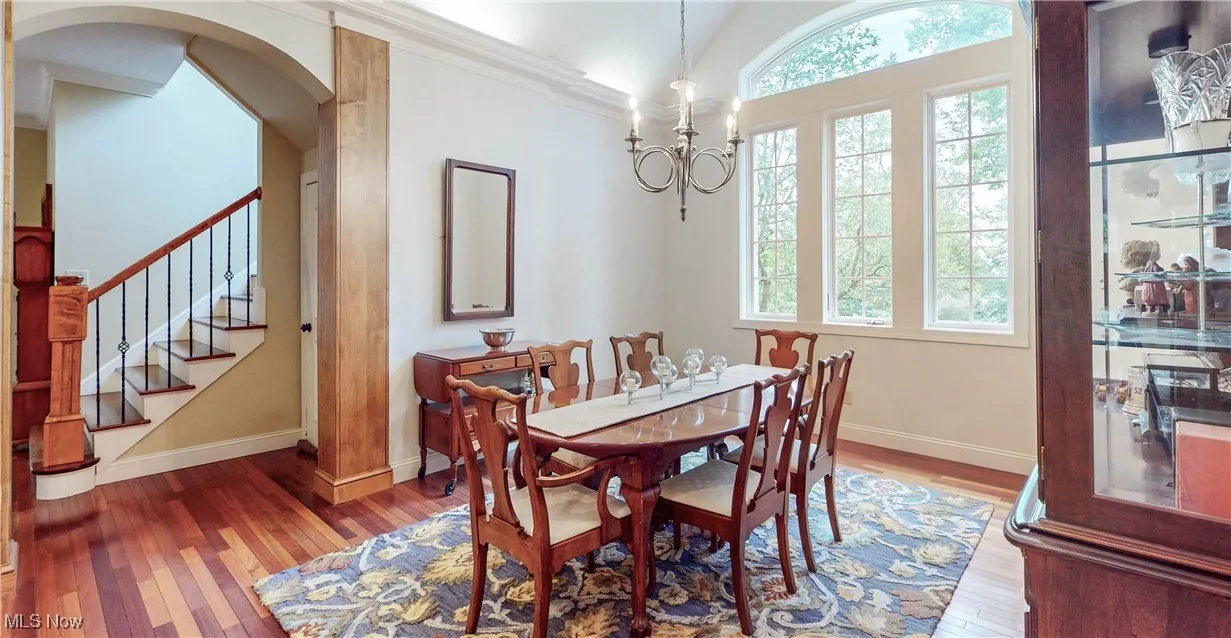 Dining space featuring wood-type flooring, arched walkways, baseboards, stairs, and ornamental molding