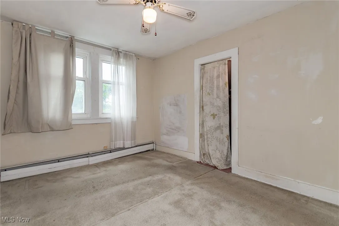 Empty room featuring baseboard heating, carpet, a ceiling fan, and baseboards