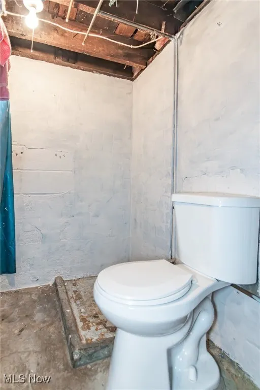 Bathroom with toilet and unfinished concrete floors