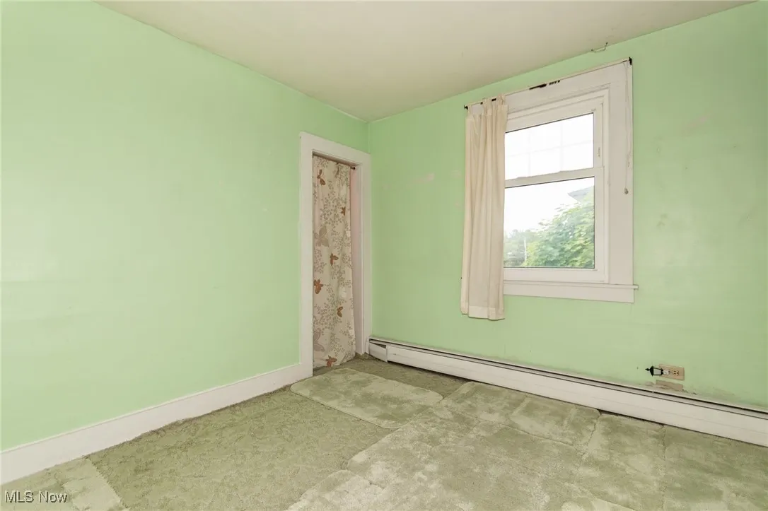 Unfurnished room featuring baseboard heating and baseboards