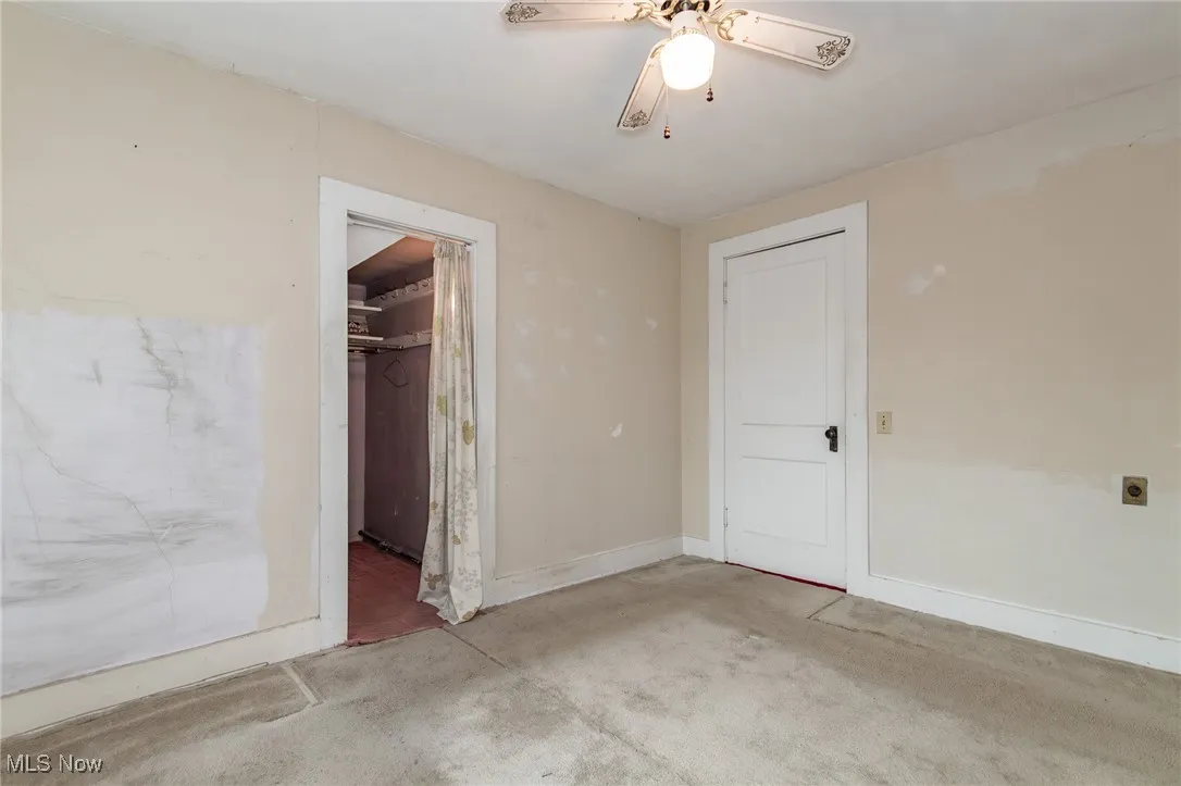 Unfurnished bedroom featuring carpet, a walk in closet, baseboards, a closet, and a ceiling fan