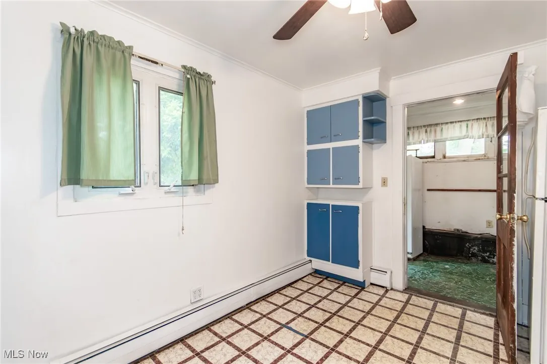 Unfurnished room featuring ornamental molding, a ceiling fan, a baseboard radiator, and light flooring