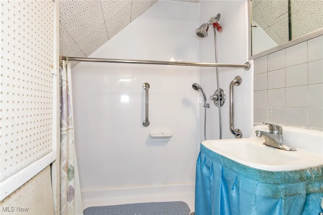 Bathroom with a shower with shower curtain and a sink
