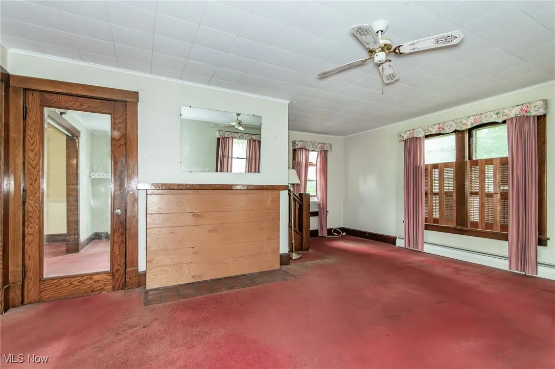 Unfurnished living room with ceiling fan, carpet flooring, crown molding, and baseboards