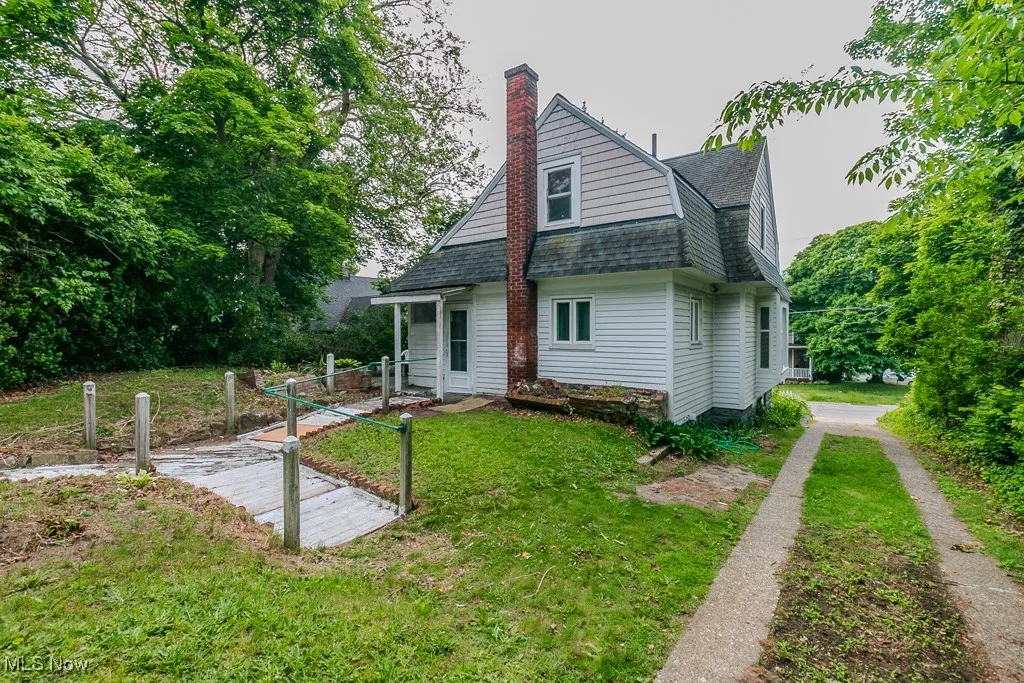 Rear view of property with a lawn, roof with shingles, and a chimney