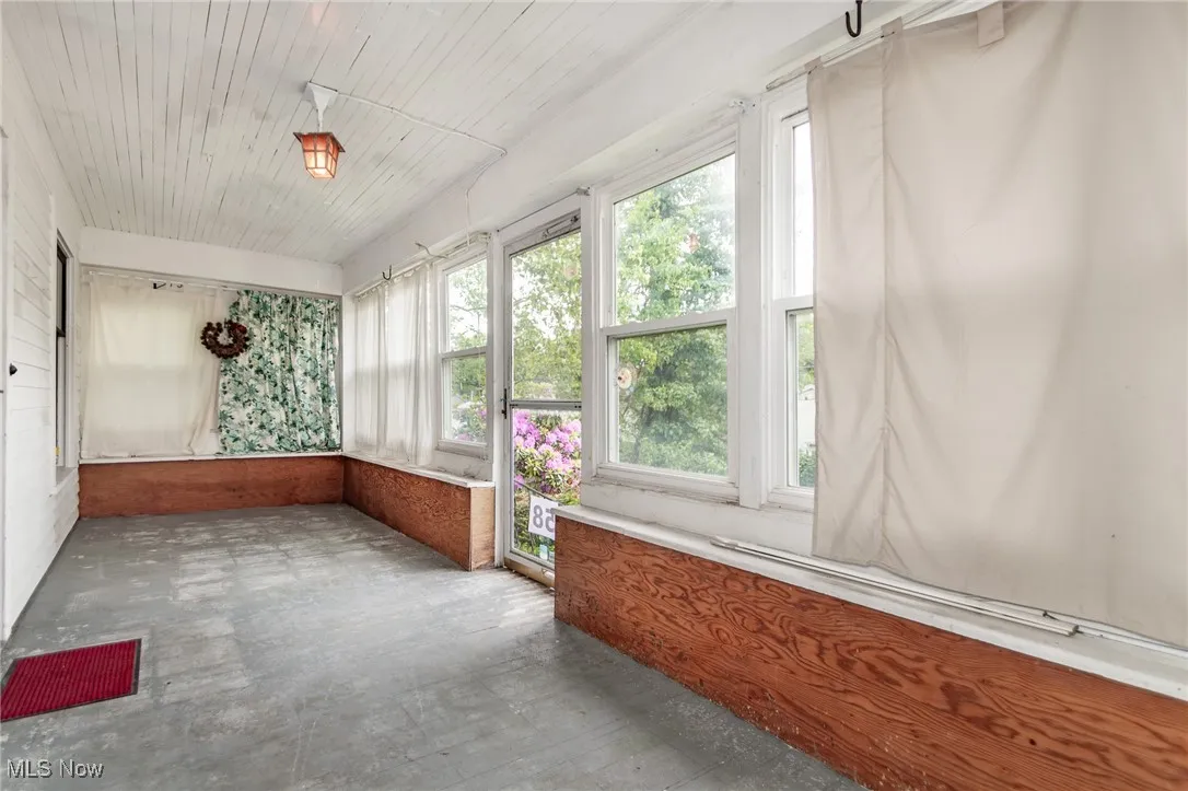 Unfurnished sunroom featuring concrete flooring