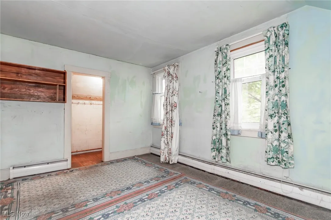 Unfurnished bedroom featuring a baseboard heating unit