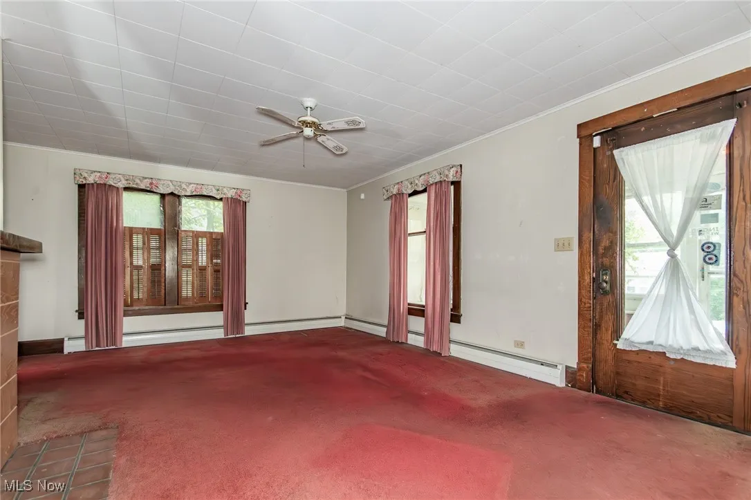 Unfurnished living room with carpet floors, a ceiling fan, and crown molding