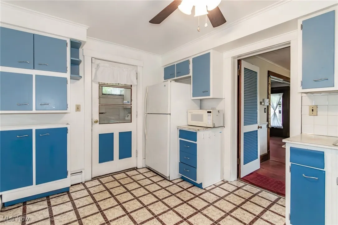 Kitchen featuring blue cabinets, white appliances, crown molding, healthy amount of natural light, and light countertops