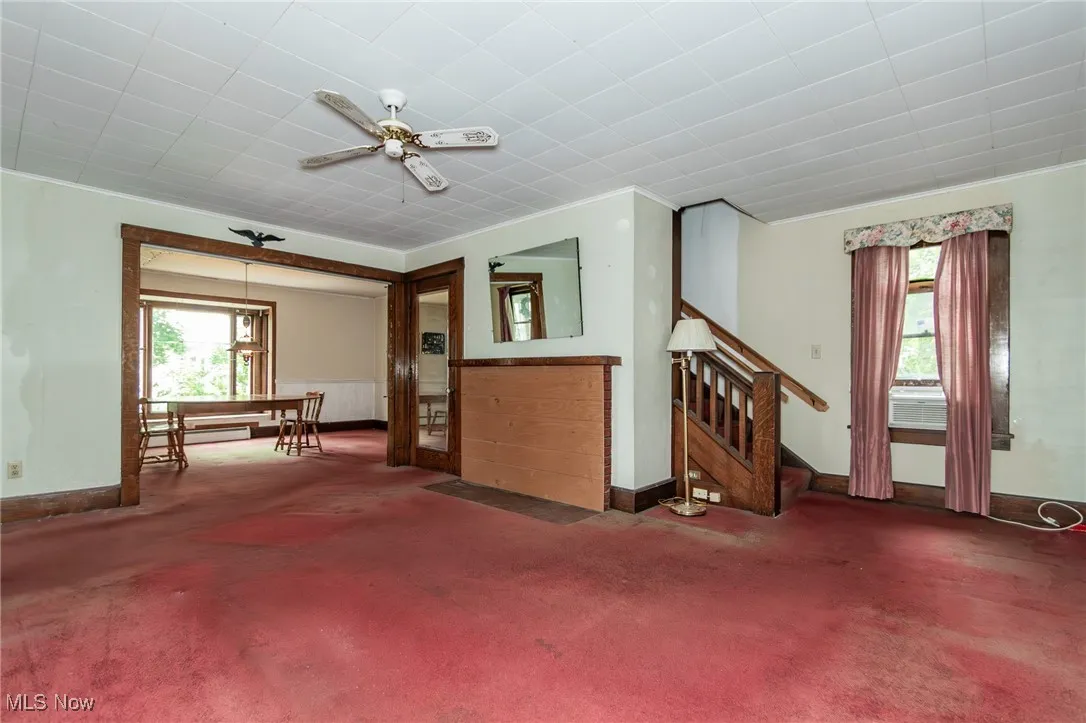 Spare room featuring stairs, carpet flooring, baseboards, a baseboard radiator, and a ceiling fan