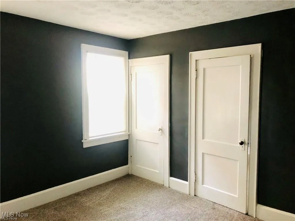 Unfurnished bedroom featuring carpet, baseboards, and a textured ceiling