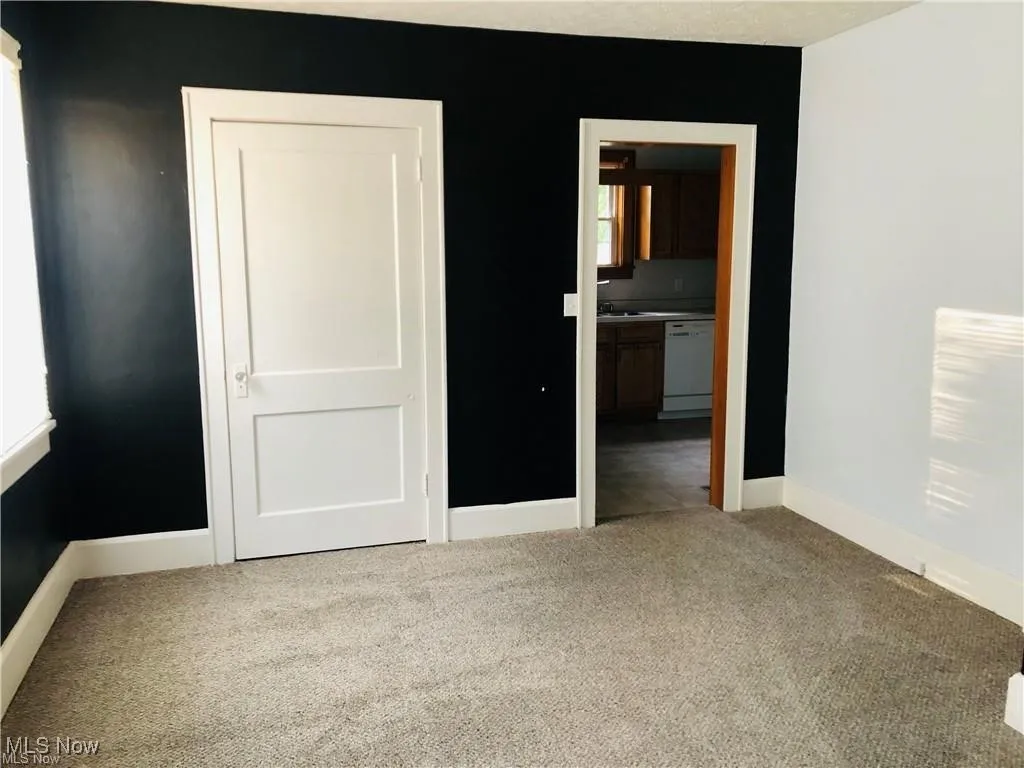 Unfurnished bedroom with carpet flooring, baseboards, and ensuite bathroom