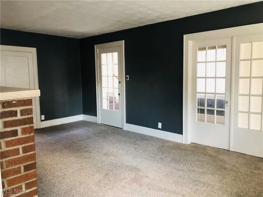 Unfurnished living room featuring carpet flooring, baseboards, and a textured ceiling