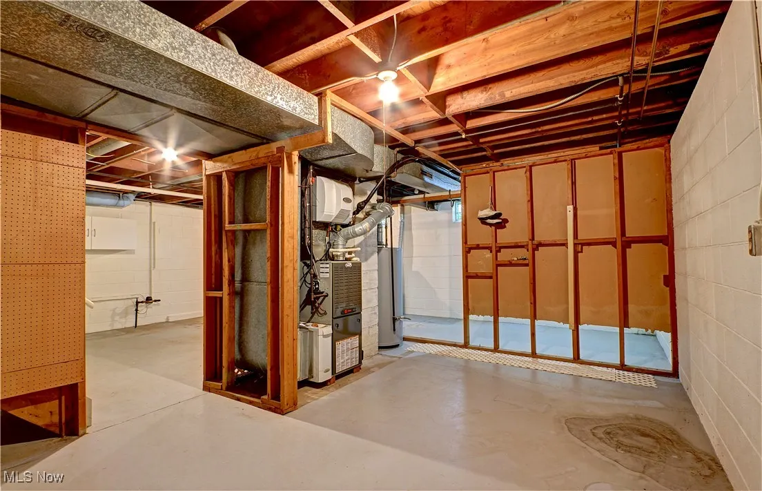 Unfinished basement featuring water heater and concrete block wall