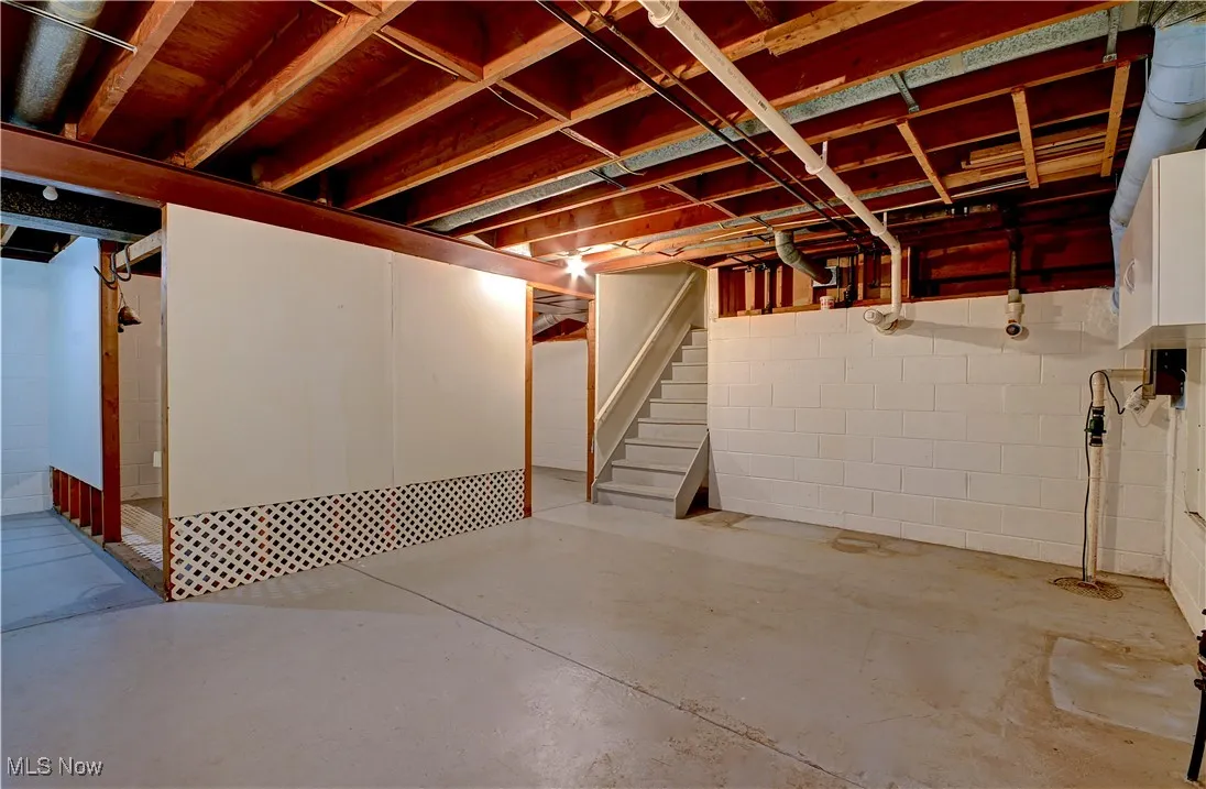 Unfinished below grade area with stairs and concrete block wall