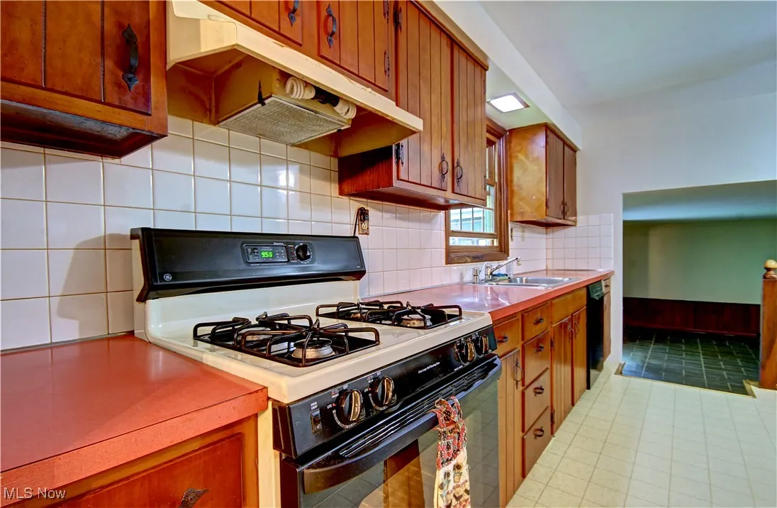 Kitchen with gas range oven, a sink, light countertops, and dishwasher