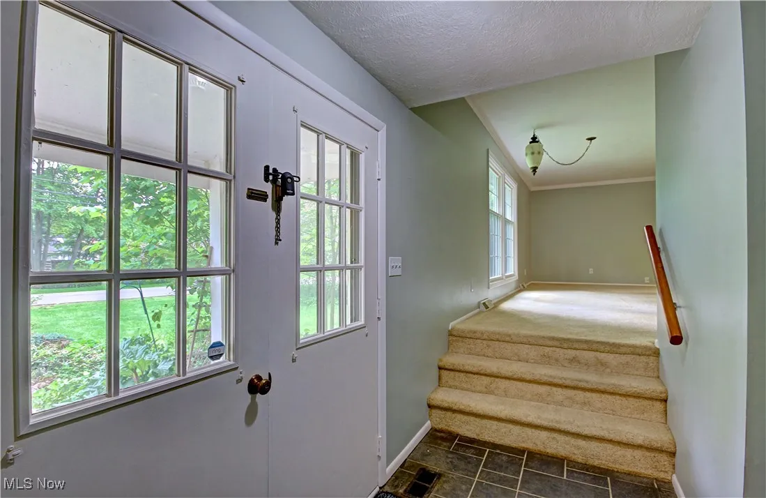 Doorway to outside with baseboards, stairway, stone finish flooring, and a textured ceiling
