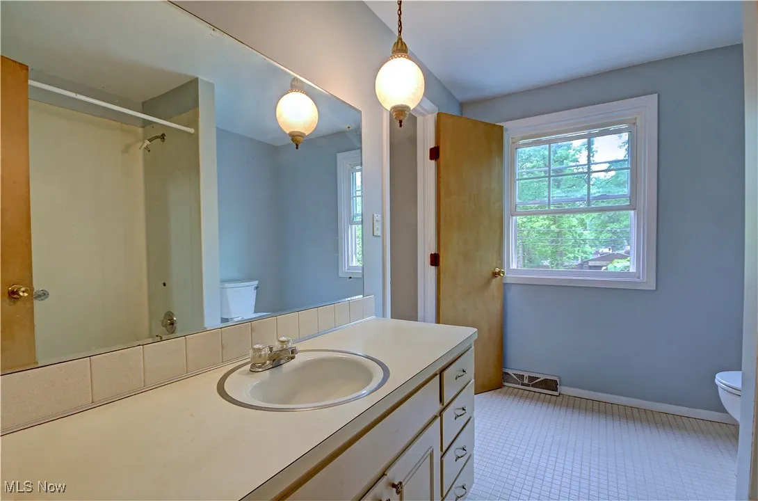 Bathroom featuring toilet, vanity, a shower, baseboards, and tile patterned floors