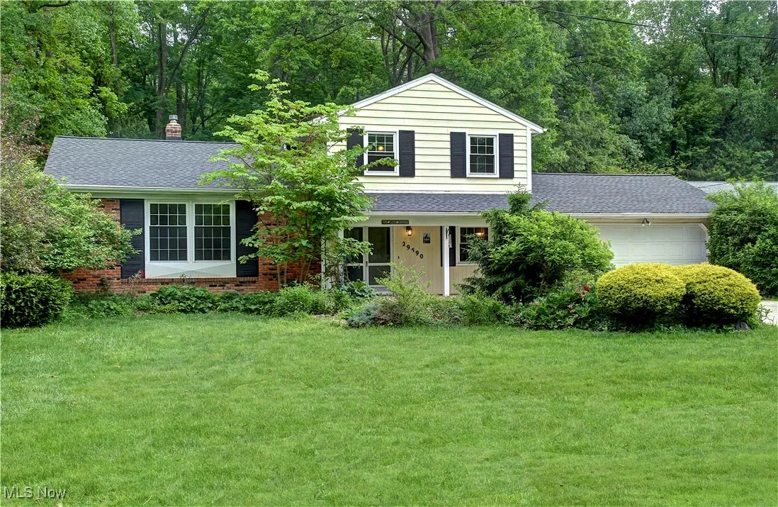 Traditional-style house with a garage, a front yard, and roof with shingles