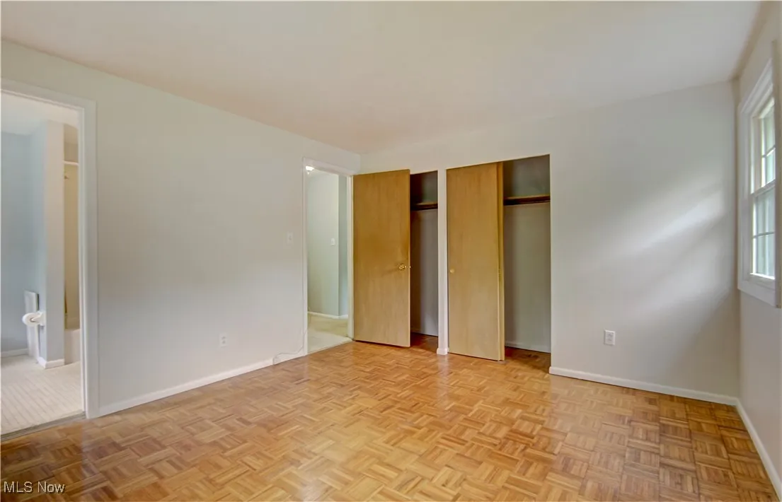 Unfurnished bedroom featuring multiple closets, baseboards, and ensuite bathroom