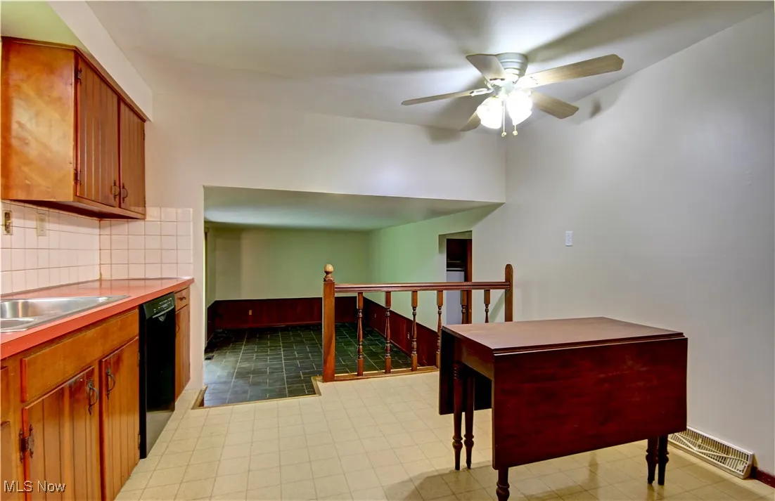 Kitchen featuring ceiling fan, tasteful backsplash, light countertops, black dishwasher, and baseboards