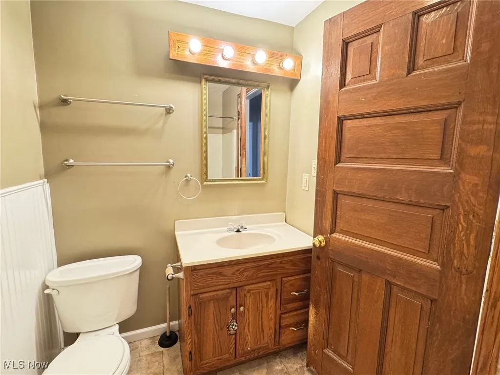 First floor Bathroom with vanity, toilet, tile patterned floors, and baseboards