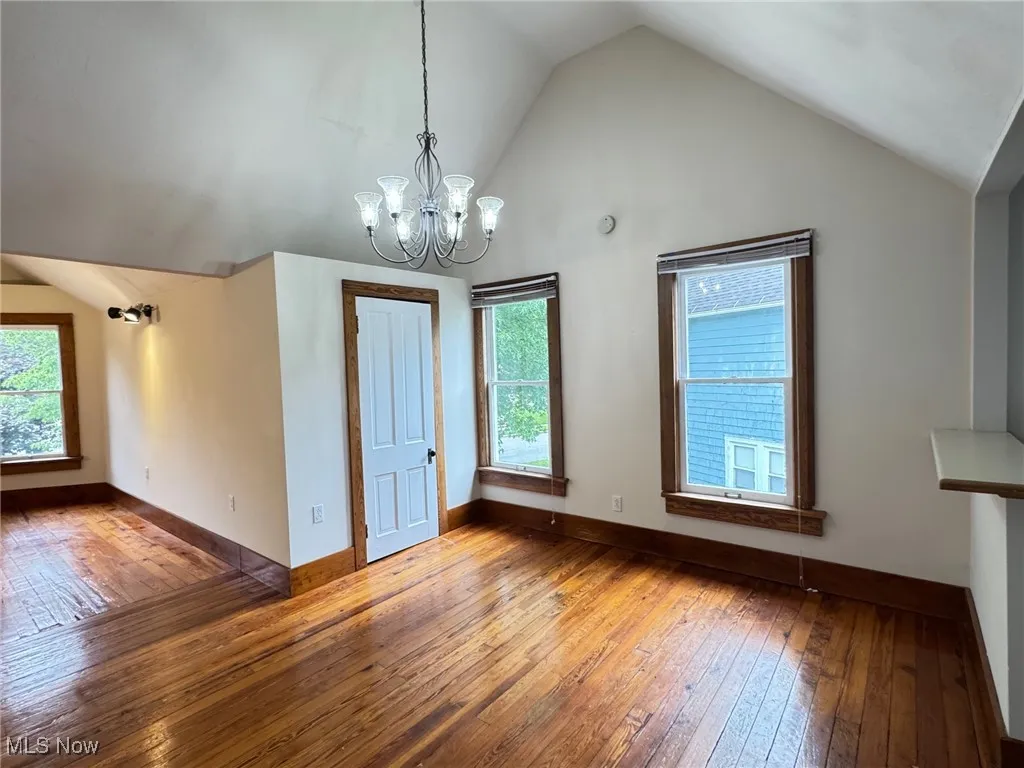 2nd floor dining area featuring vaulted ceiling, hardwood / wood-style flooring, a chandelier, and baseboards