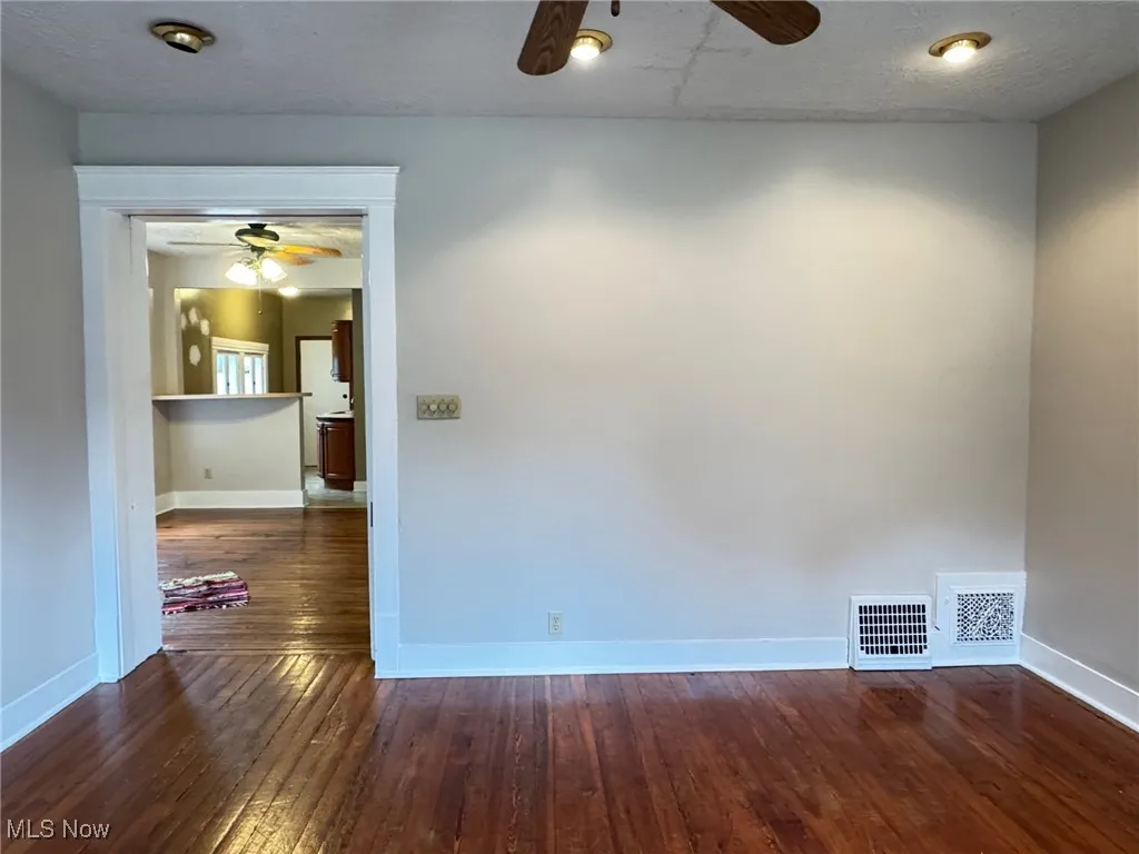 Empty room featuring a ceiling fan, hardwood / wood-style floors, and baseboards