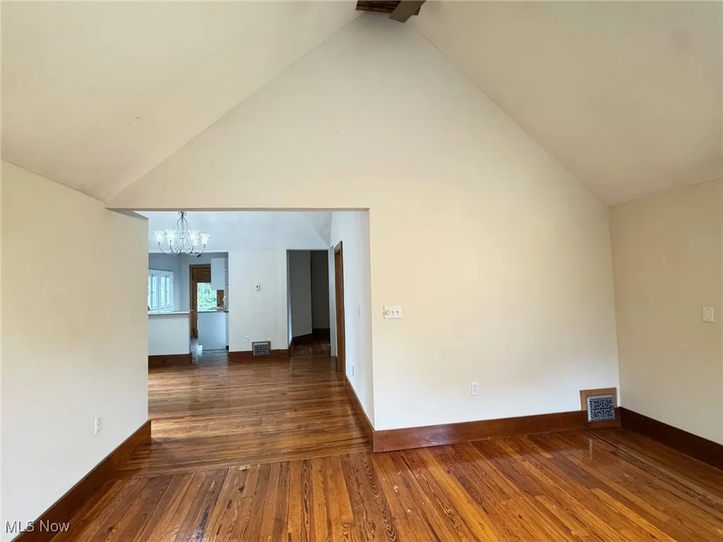 2nd floor living room with a chandelier, high vaulted ceiling, hardwood / wood-style flooring, and baseboards