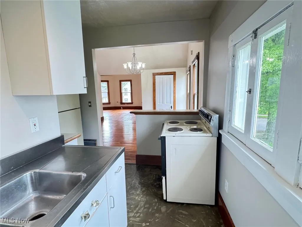 2nd floor Kitchen with electric range, plenty of natural light, a chandelier, and white cabinetry