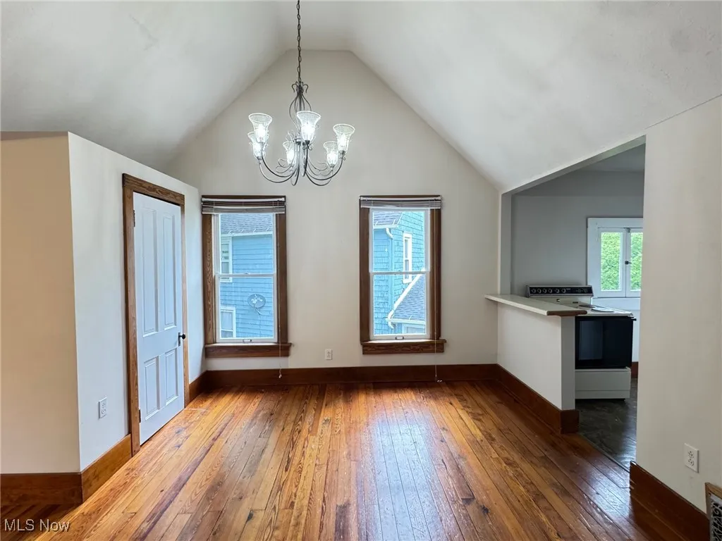 2nd floor dining area with wood-type flooring, a chandelier, lofted ceiling, and baseboards