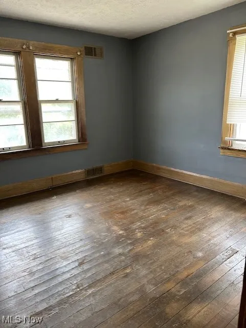 Spare room with dark wood-type flooring, baseboards, and a textured ceiling