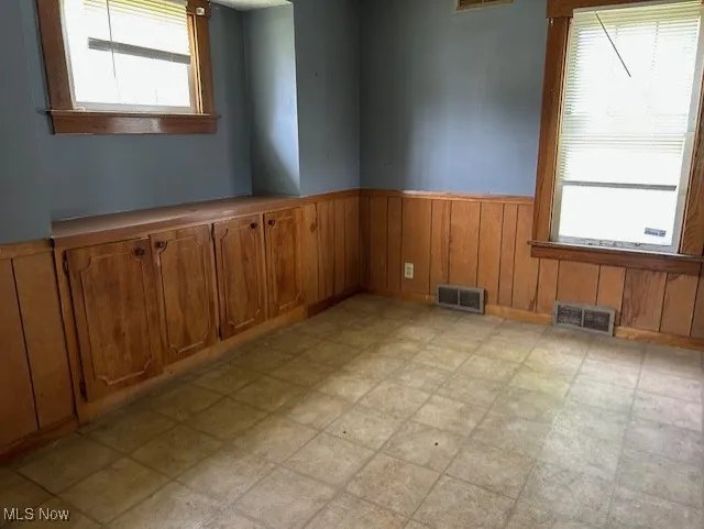 Spare room featuring a wainscoted wall, plenty of natural light, and wooden​​‌​​​​‌​​‌‌​‌‌​​​‌‌​‌​‌​‌​​​‌​​ walls