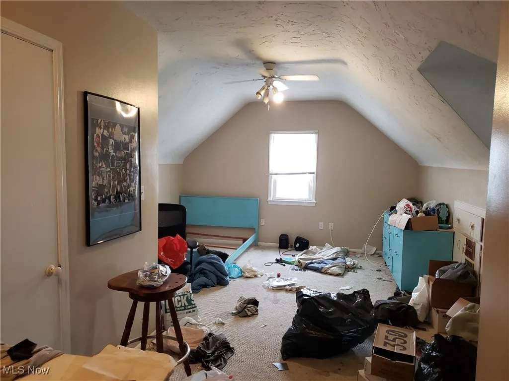 Additional living space with lofted ceiling, carpet floors, and a ceiling fan