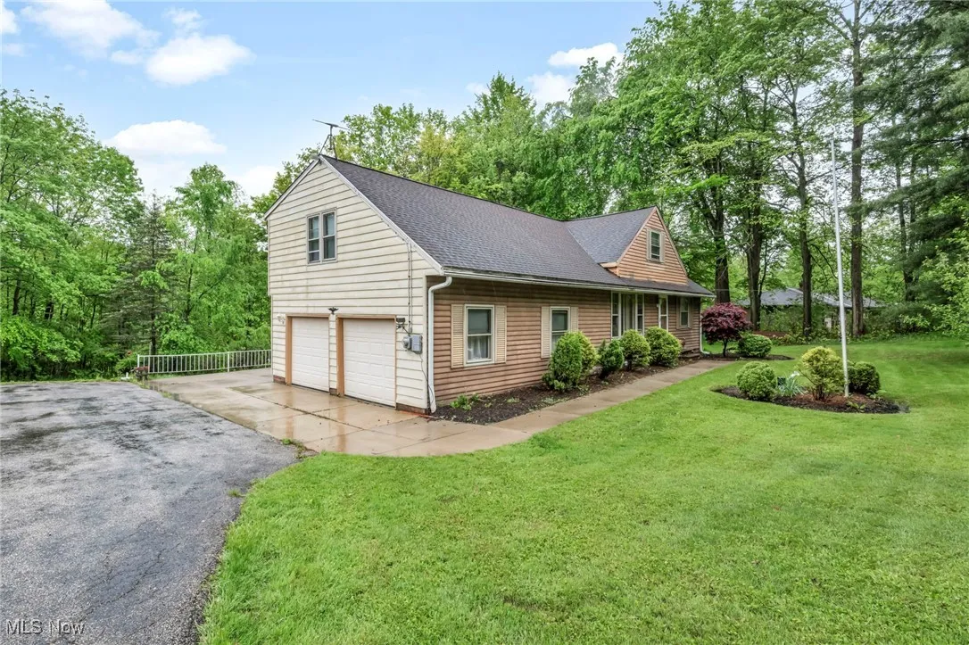 View of side of property featuring a shingled roof, asphalt driveway, and a garage