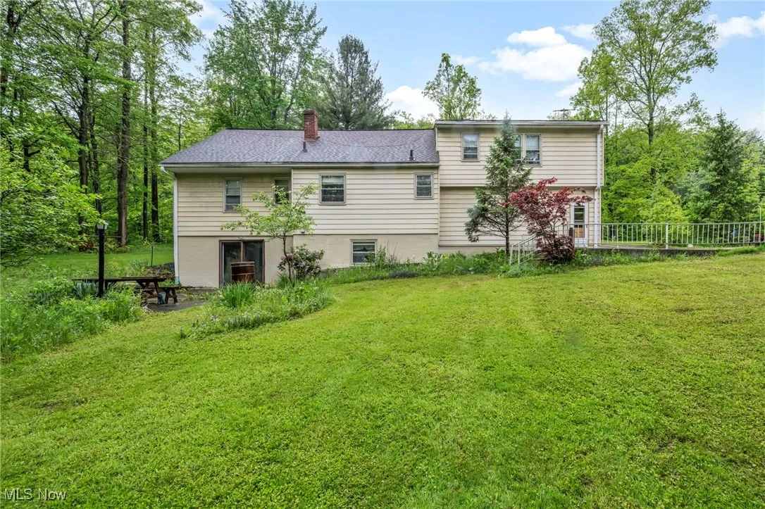 Back of property with a chimney and a lawn