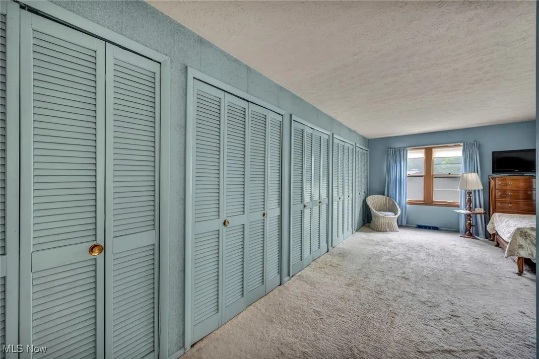 Carpeted bedroom featuring a textured ceiling and two closets