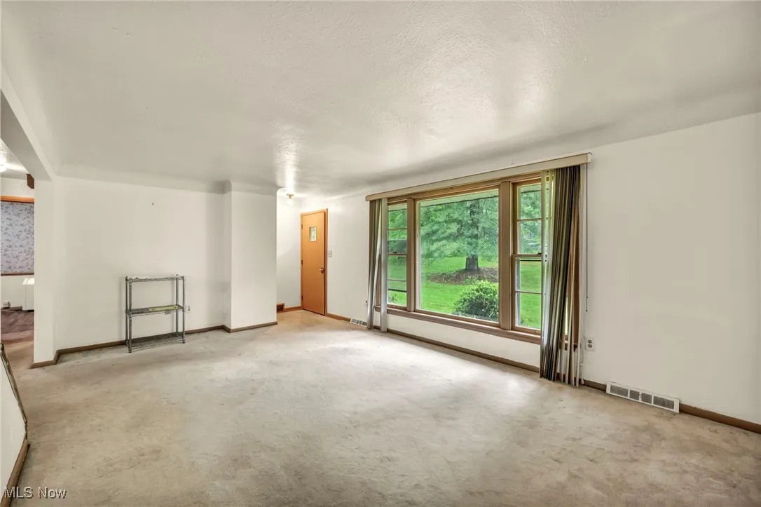 Unfurnished living room featuring carpet floors, baseboards, and a textured ceiling