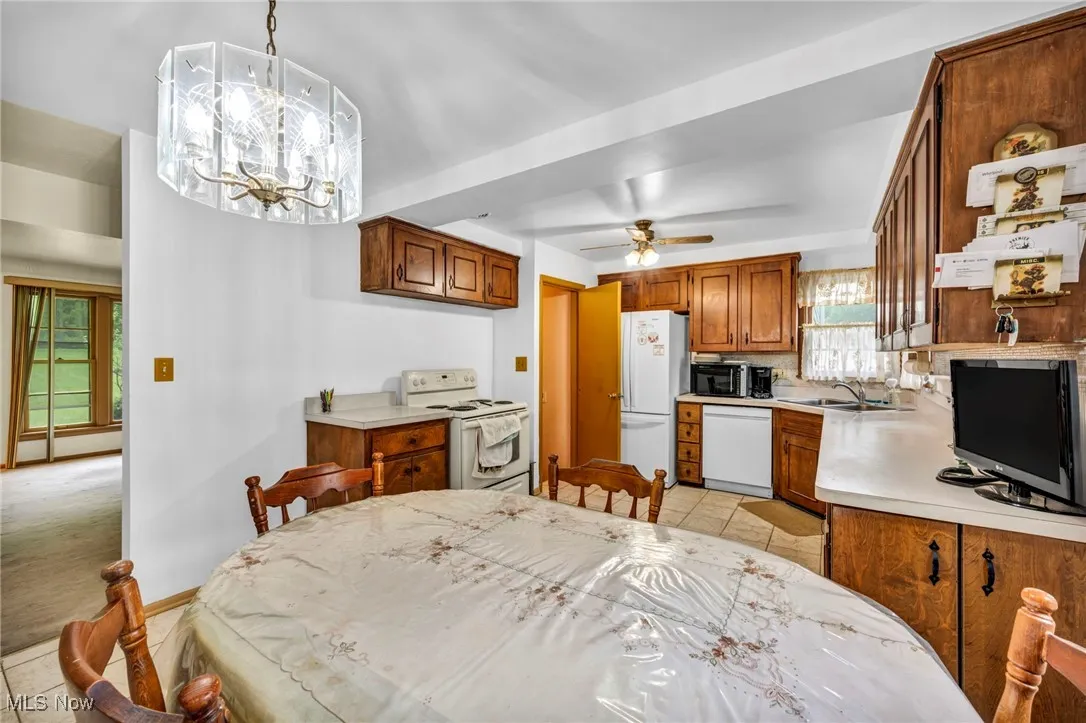 Dining area featuring light tile patterned floors, ceiling fan, and a chandelier