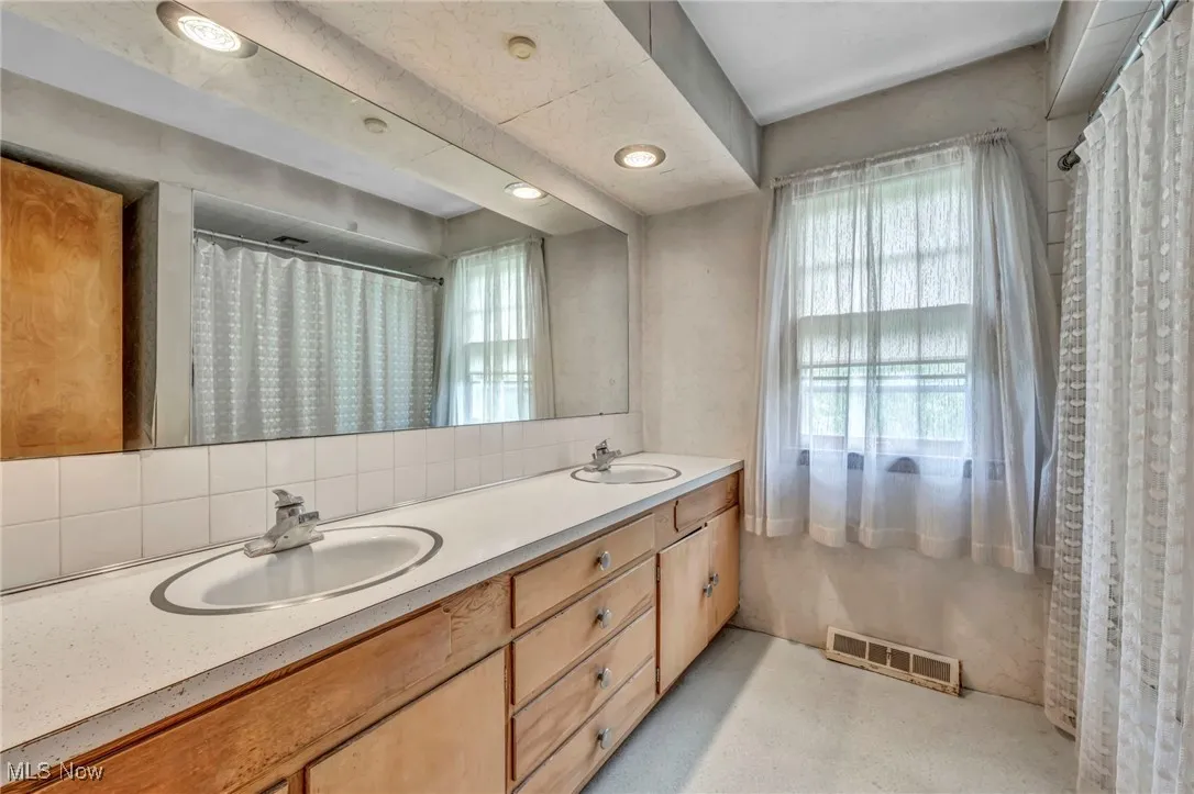 Bathroom featuring double vanity and backsplash