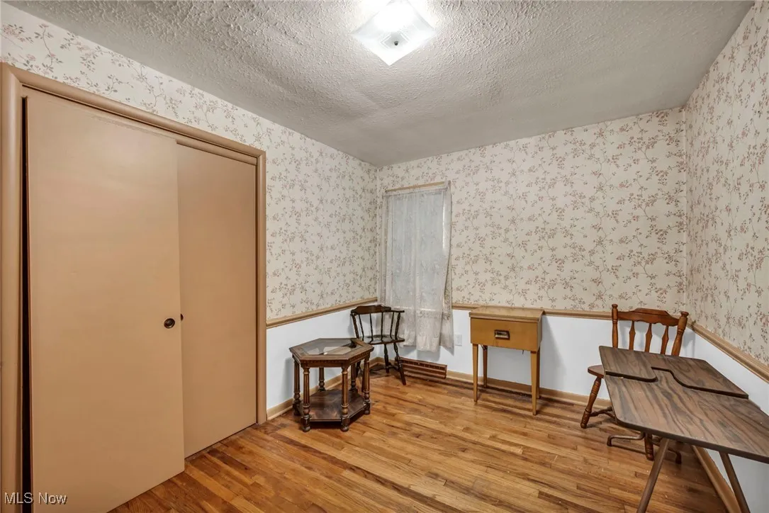 Sitting room featuring wood-type flooring, wallpapered walls, and a textured ceiling