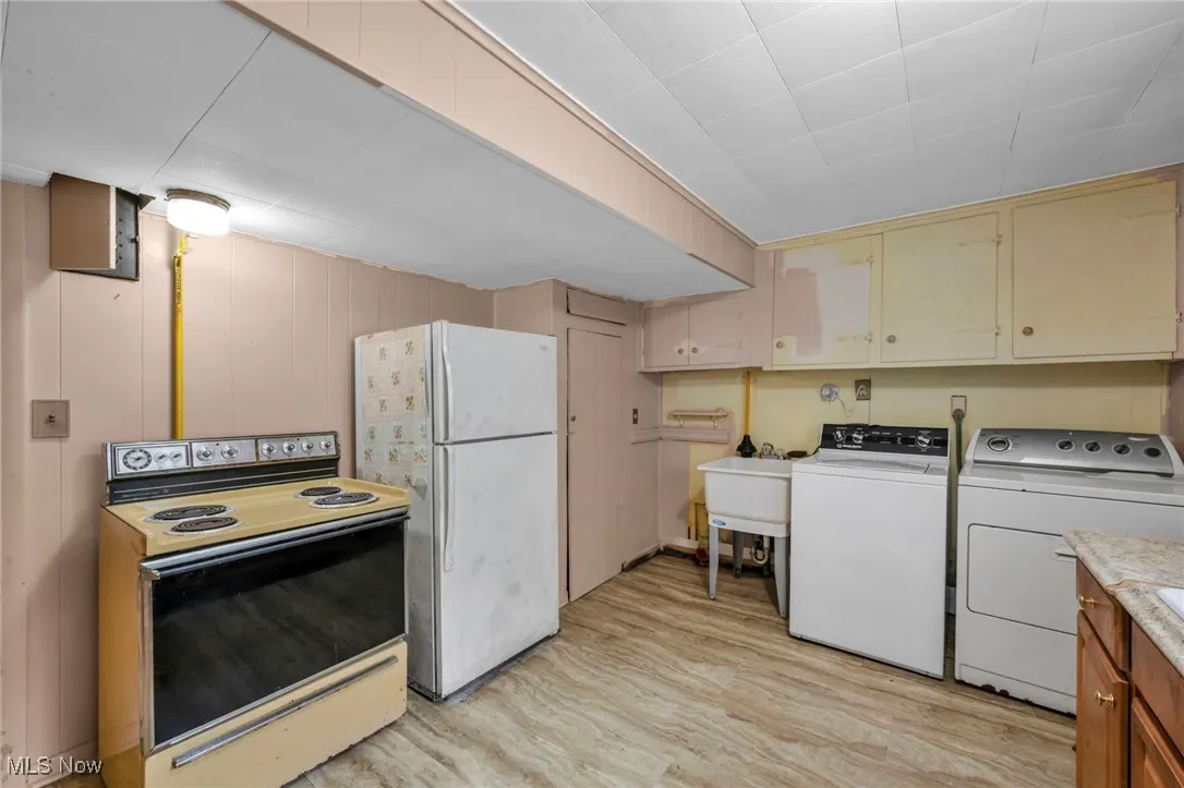 Laundry area with separate washer and dryer and light wood-type flooring