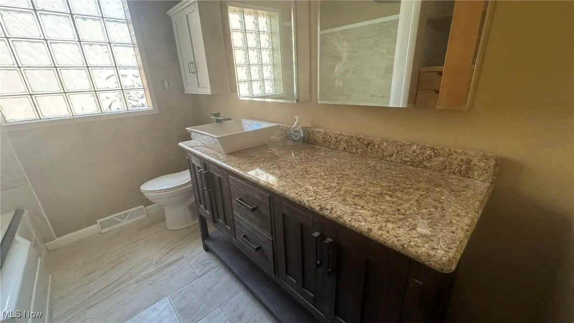 Bathroom featuring vanity, toilet, and baseboards