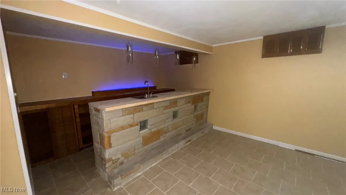 Indoor wet bar with baseboards and crown molding