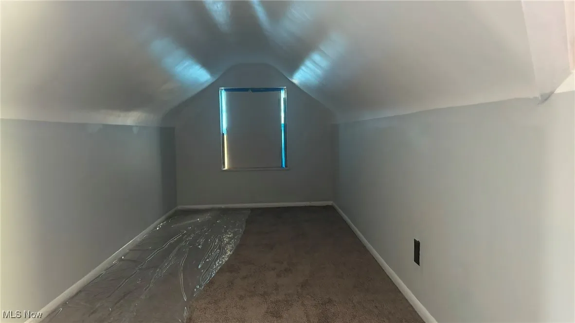 Additional living space with lofted ceiling and baseboards