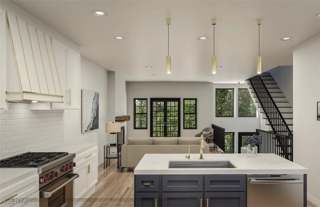 Kitchen featuring appliances with stainless steel finishes, a sink, light countertops, open floor plan, and tasteful backsplash